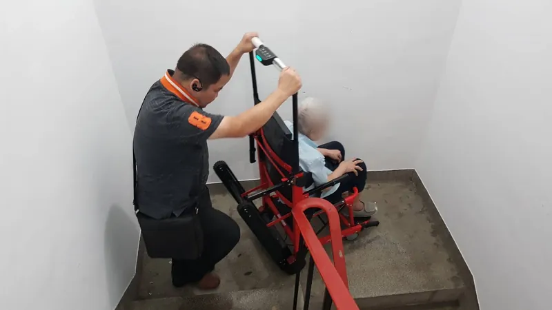 工作人員操作紅色爬梯機，在樓梯間協助長輩上下樓
