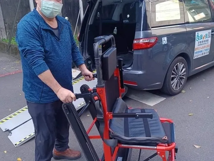 工作人員在無障礙車旁，扶著紅色履帶爬梯機